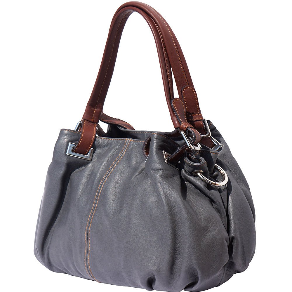 Angled view of valentina sling backpack showing brown strap and silver rings