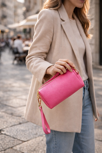 Person holding a pink clutch bag on a city street