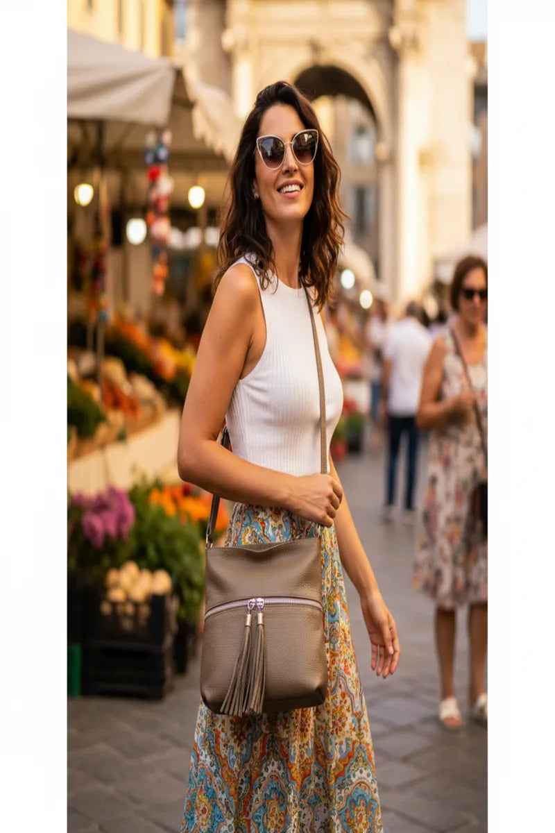 Woman carrying an Italian leather crossbody bag while walking through a market in Italy.